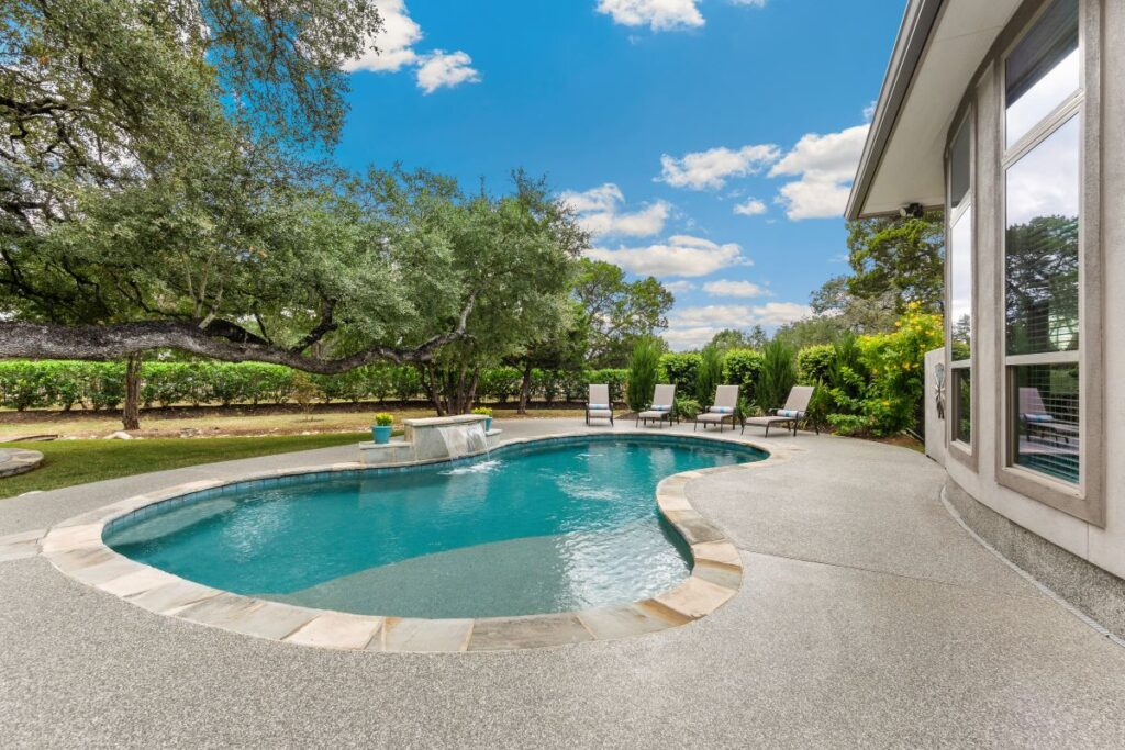 A large luxury home with a pool and lush green landscaping