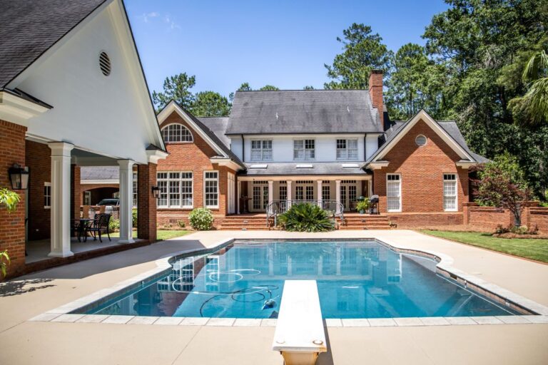 Large Blue Swimming Pool Outdoors with Brick Pool House and Home with pool Cleaner running
