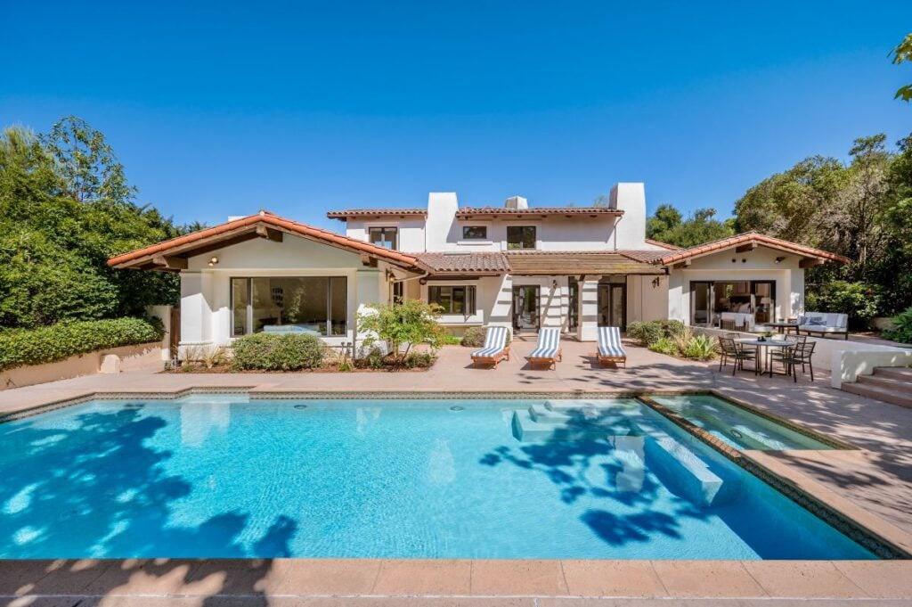 a house with a pool in the backyard and lots of greenery around it