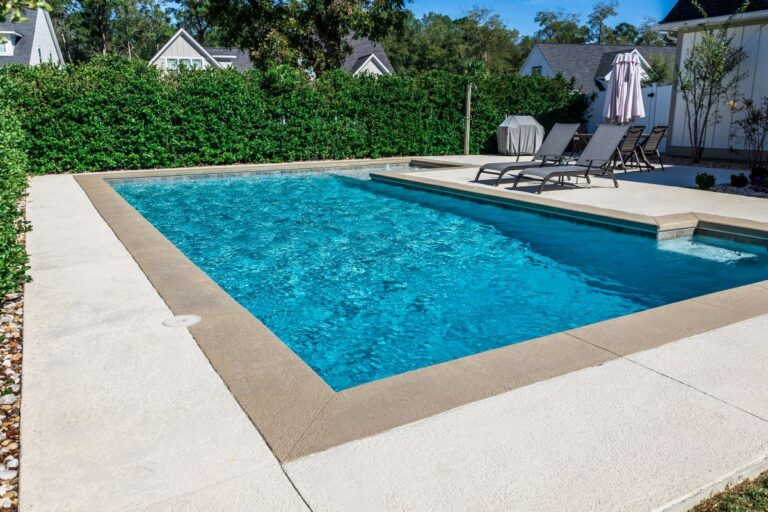 rectangular new swimming pool with tan concrete edges