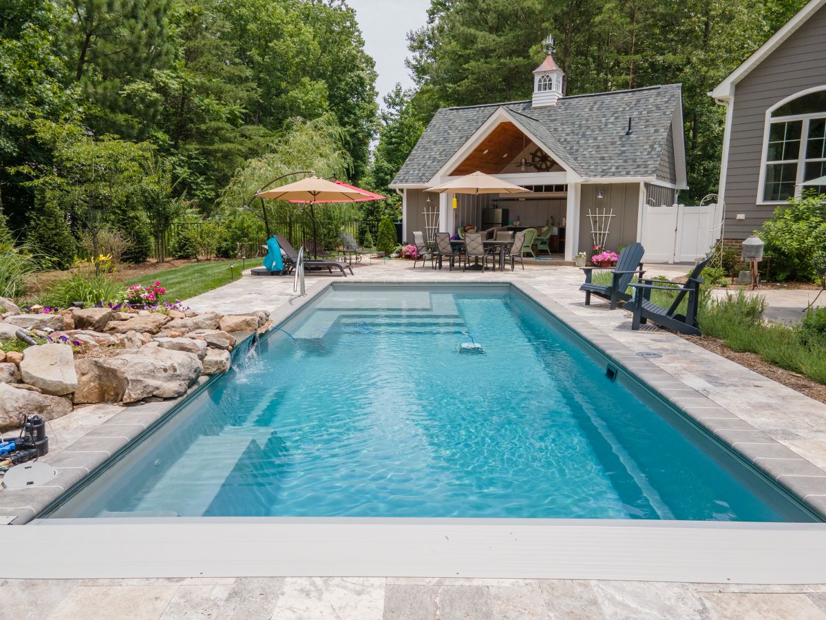 River Pools M35 in Granite Gray with a cascade, natural stone patio, and concrete paver coping