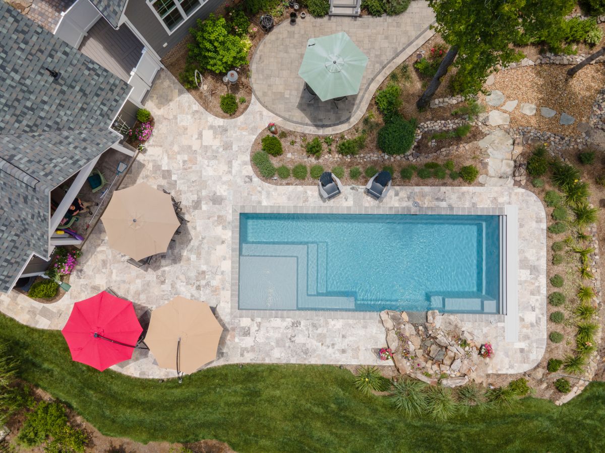 Aerial view of a rectangualr pool in a backayrd with stone patio