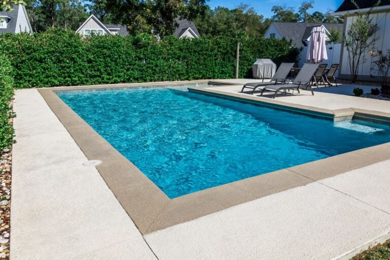 rectangular new swimming pool with tan concrete edges